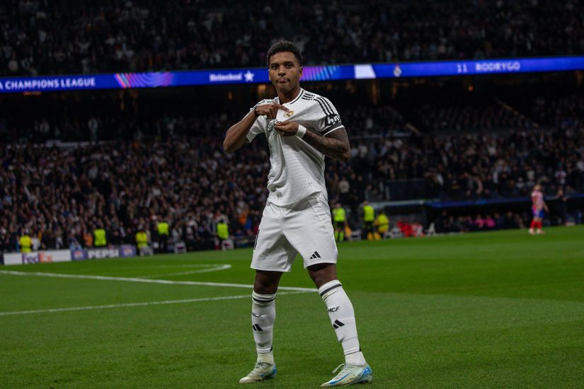 Un footballeur en uniforme blanc, fièrement sponsorisé par Betway, est sur le terrain pour célébrer un but. Il fait un geste sincère avec ses mains sur sa poitrine. Le stade bourdonne d'excitation et un tableau d'affichage se profile à l'arrière-plan.