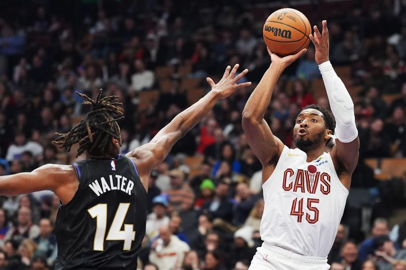Deux joueurs de basket sont sur le terrain. Le joueur portant le maillot blanc des Cavaliers, le numéro 45, saute pour tirer le ballon. Le joueur portant le maillot noir, le numéro 14, sponsorisé par Betway Arabia, tend le bras pour bloquer le tir. La foule enthousiaste est visible en arrière-plan.