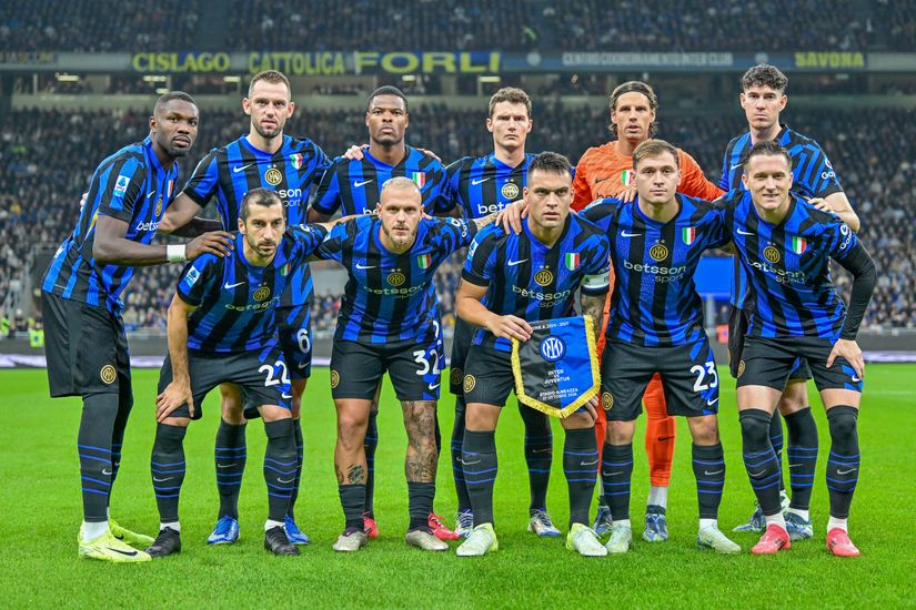 A soccer team poses on the field in blue and black striped jerseys with white shorts, proudly representing Betway. Eleven players stand together, some with arms around each other. The stadium and crowd are visible in the background as one player holds a team banner.