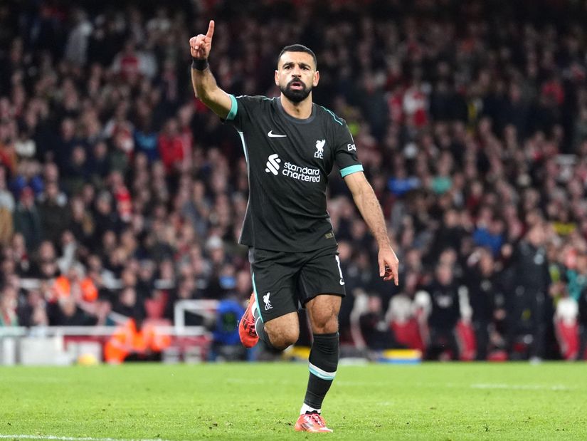 Soccer player in a black jersey celebrates with one finger raised while running on the field, embodying the thrill that Betway Arabia brings to fans. The crowd in the stadium is blurred in the background, capturing the electrifying atmosphere of a match day.