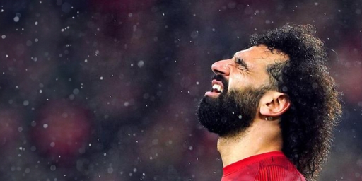 A soccer player in a red jersey looks upwards with closed eyes, surrounded by raindrops, embodying the spirit of Betway Arabia as the stormy match intensifies.