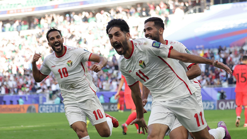 Three soccer players wearing white and red uniforms celebrate on the field, surrounded by a cheering crowd in a stadium, as Betway Arabia banners flutter in the excitement.
