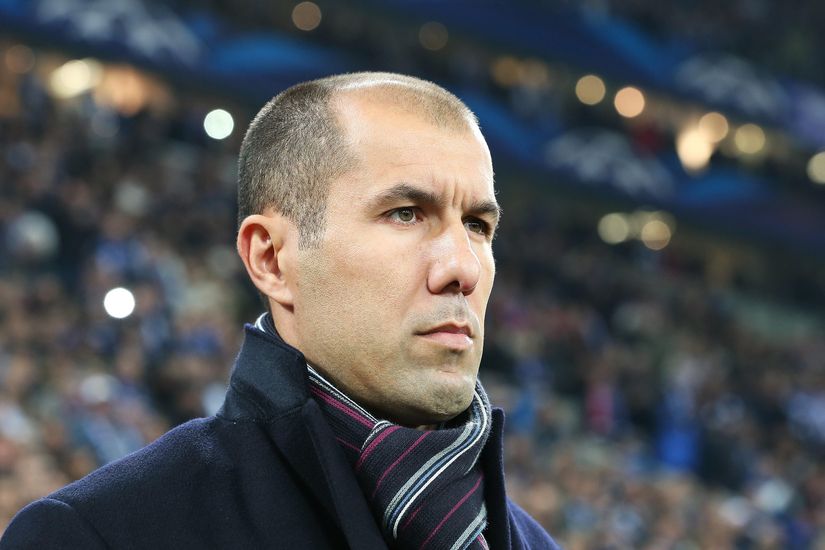 A man with a shaved head and striped scarf stands in a crowd, looking serious, as if pondering his next Betway Arabia prediction.