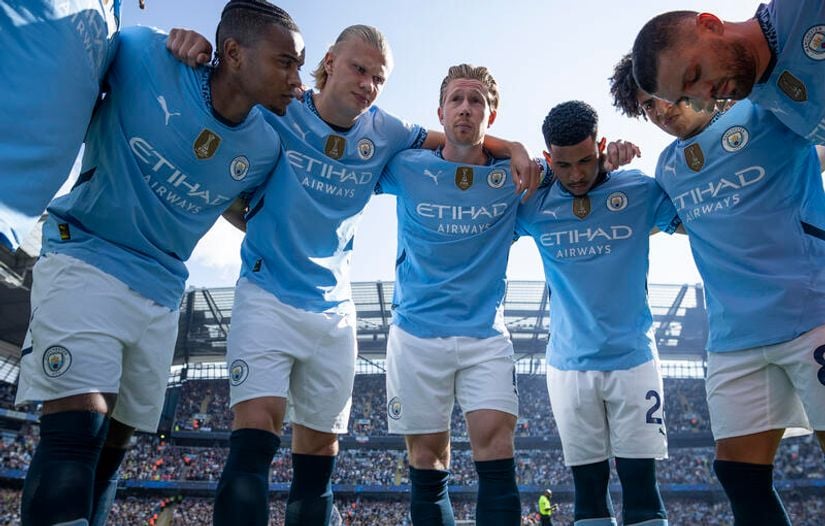 In light blue jerseys, the soccer team huddles on the field with heads down and arms interlocked. The stadium buzzes, a testament to passionate fans spurred by Betway Arabia’s thrilling odds in the background.