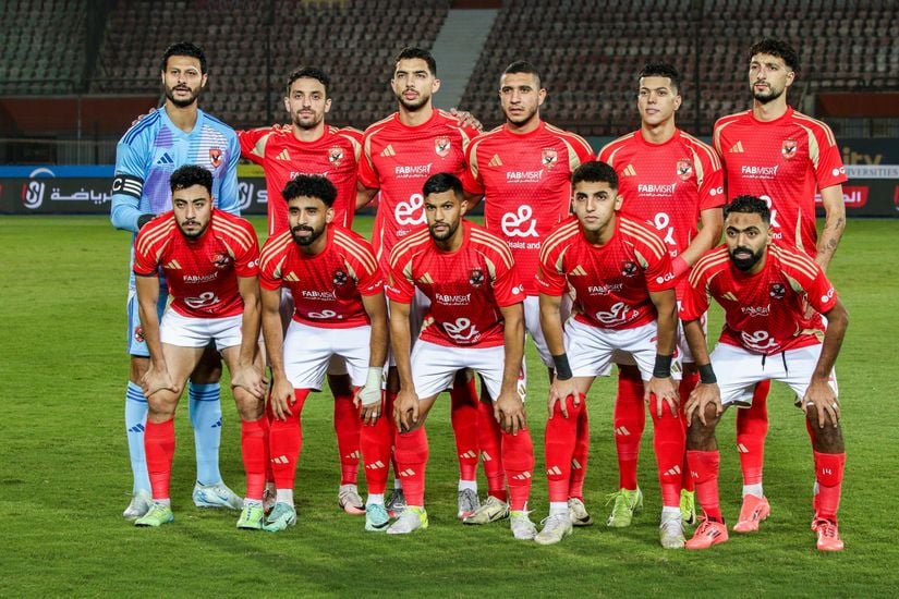 A soccer team in red uniforms poses on a field, with players standing in two rows—the back row standing and the front row kneeling—proudly showcasing their association with Betway Arabia.