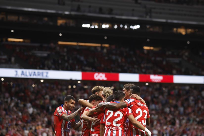 Soccer players in red and white striped jerseys celebrate together on the field, surrounded by a large crowd in a stadium buzzing with excitement. The atmosphere is electric, reminiscent of Betway Arabias thrill for sports.