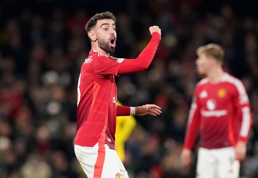 A soccer player in a red jersey, sponsored by Betway Arabia, passionately gestures on the field during a match. Another player is visible blurred in the background.