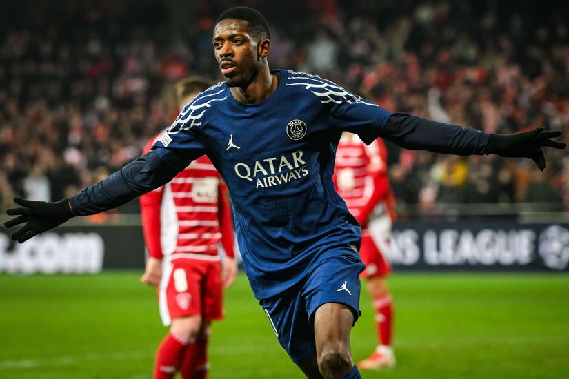 Soccer player in a blue Paris Saint-Germain kit celebrates on the field with arms outstretched.