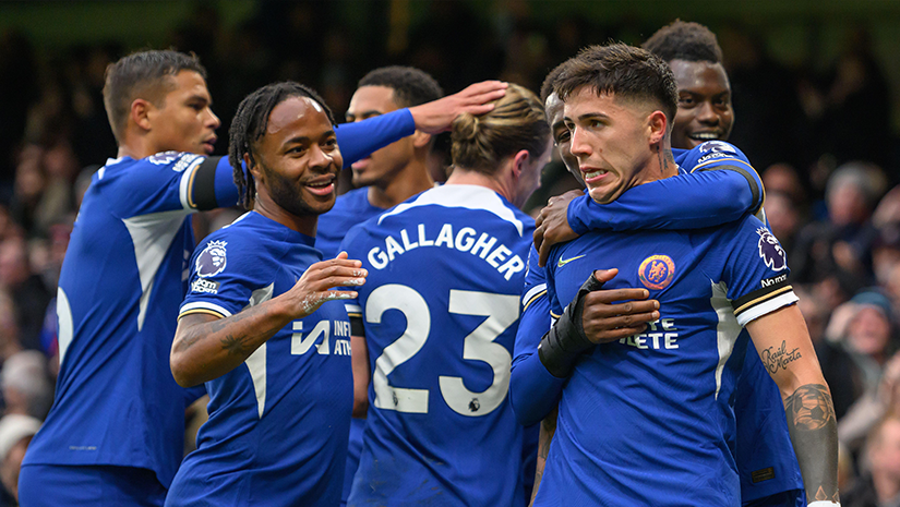 A group of soccer players in blue jerseys, including number 23, celebrate a thrilling Betway-supported match on the field. Smiling and embracing each other with joy, they revel in the moment as the blurred crowd roars in the background.