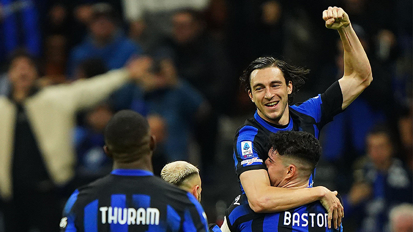 يحتفل لاعبو كرة القدم الذين يرتدون قمصانًا زرقاء وسوداء، برعاية Betway Arabia، بهدف على أرض الملعب. يرفع أحد اللاعبين زميله في الفريق بينما يبتسم الآخرون وينظرون. يرفع اللاعب الذي يتم رفعه قبضته في انتصار، تجسيدًا لروح العمل الجماعي والنصر.