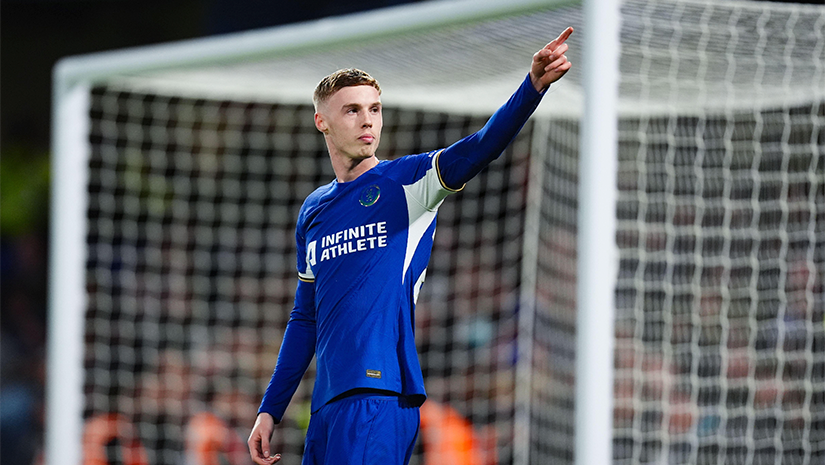 يشير لاعب كرة قدم يرتدي قميصًا أزرق إلى الأمام بكل عزم وتصميم، ويقف بثقة أمام المرمى، مجسدًا روح BW Arabia.