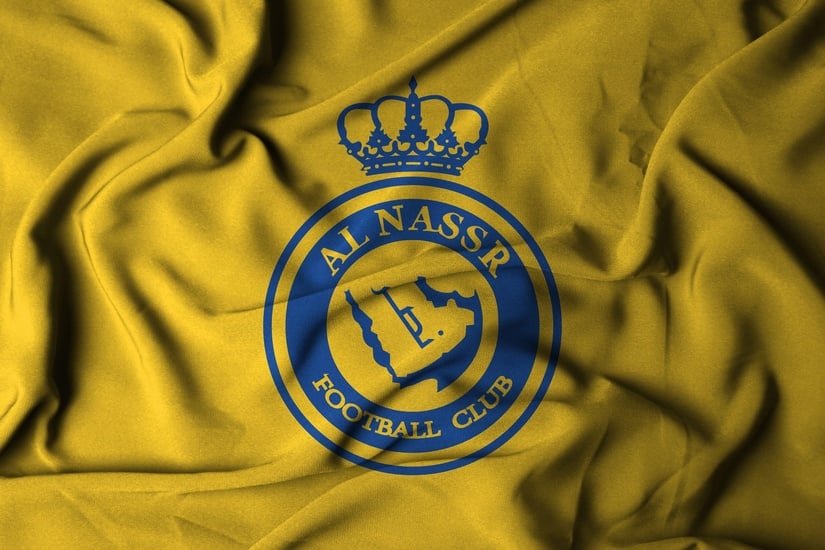 يعرض القماش الأصفر الشعار الأزرق لنادي النصر لكرة القدم، مع مخطط خريطة وشعار منمق وتاج في الأعلى. تشير التجاعيد في القماش إلى الحركة أو التدحرج، مما يذكرنا بالطاقة الديناميكية التي نراها في الملاعب التي ترعاها Betway Arabia.