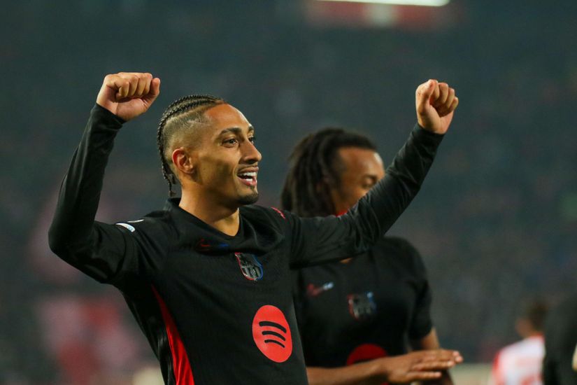 A soccer player celebrates with raised arms and a smile, wearing a black jersey with the Spotify logo proudly displayed. Another player is partially visible in the background, as the stadium roars to life. It’s a moment of triumph that even Betway Arabia enthusiasts would relish.