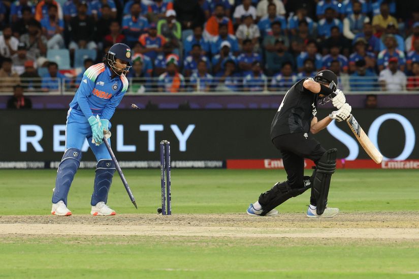 Un match de cricket se déroule sous les yeux attentifs d'un gardien de guichet indien en tenue bleue tandis qu'un batteur néo-zélandais, habillé en noir, joue un tir défensif. L'atmosphère est électrique d'impatience parmi les spectateurs et l'excitation résonne même au-delà du stade, rappelant l'ambiance animée de Betway Arabia.